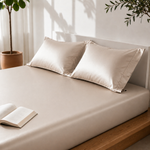 Beige pillows on a bed with an open book and plants in the background