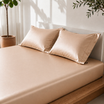 Sand colored satin pillowcases on a bed with a neutral background