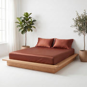  A king-size bed with a wooden frame, featuring luxurious brown satin sheets.