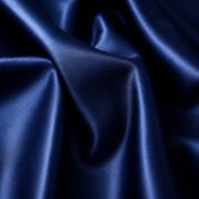 A close-up of draped satin fabric in a deep navy blue color, showing the smooth texture and sheen of the material.